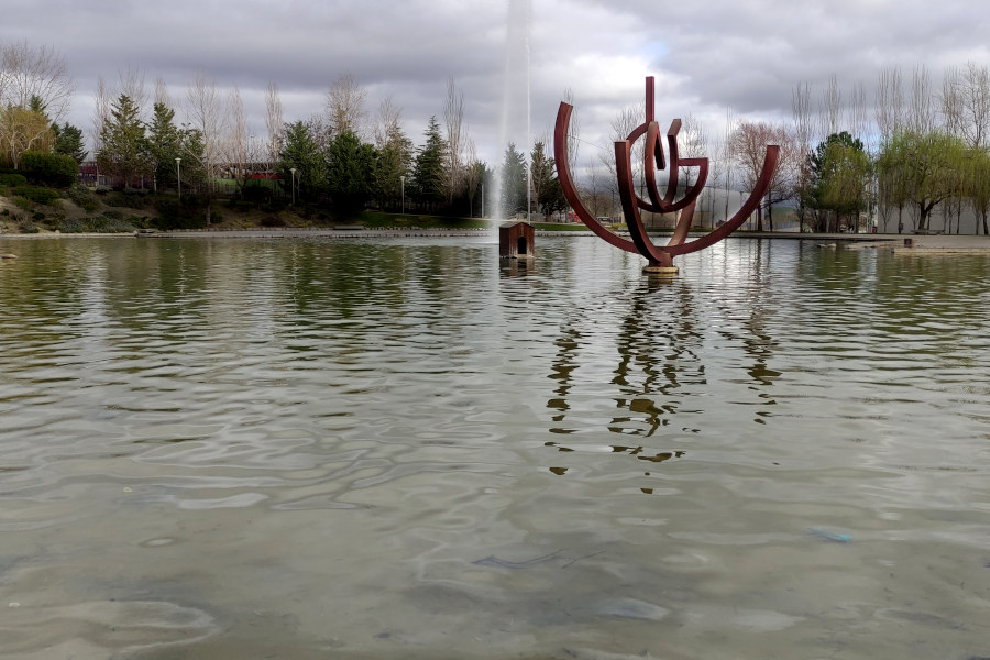 Un espacio acuático con una escultura como una esfera virtual y fuentes con fondo de árboles