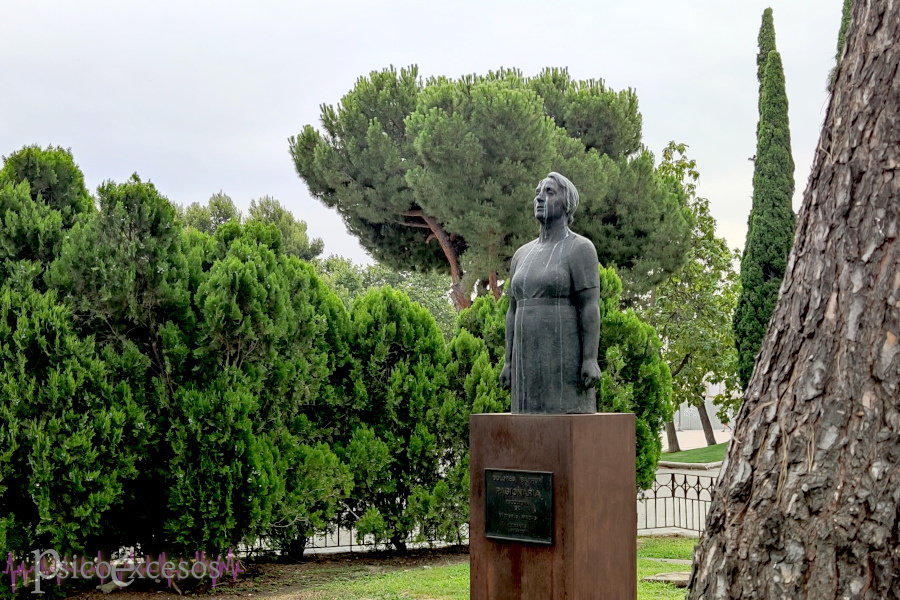 Estatua de la Pasionaria sobre un pedestal entre árboles, con marcas que semejan lágrimas